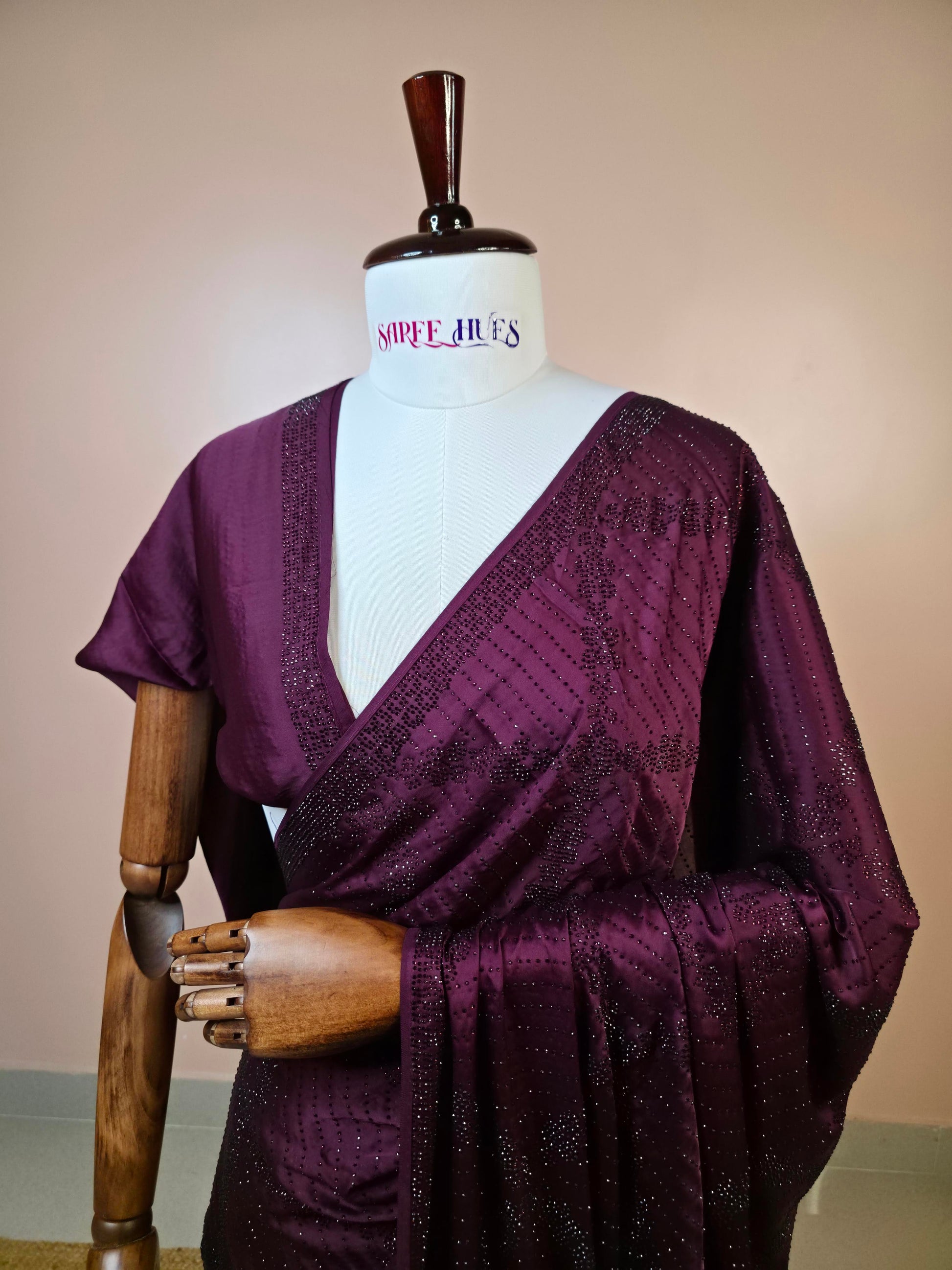 Deep wine satin silk saree with geometric Swarovski crystal work and bead embellishment on mannequin.